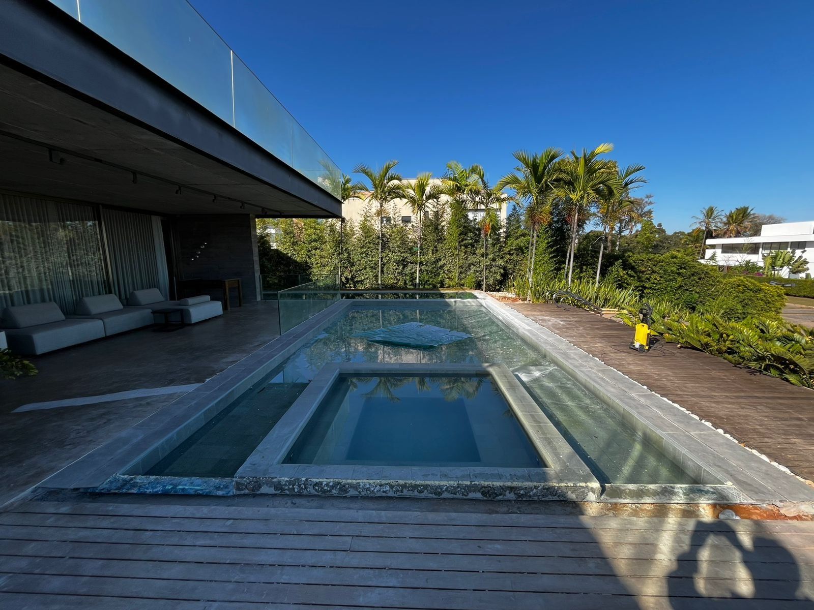 Piscina com spa integrado e deck de madeira em casa de alto padrão