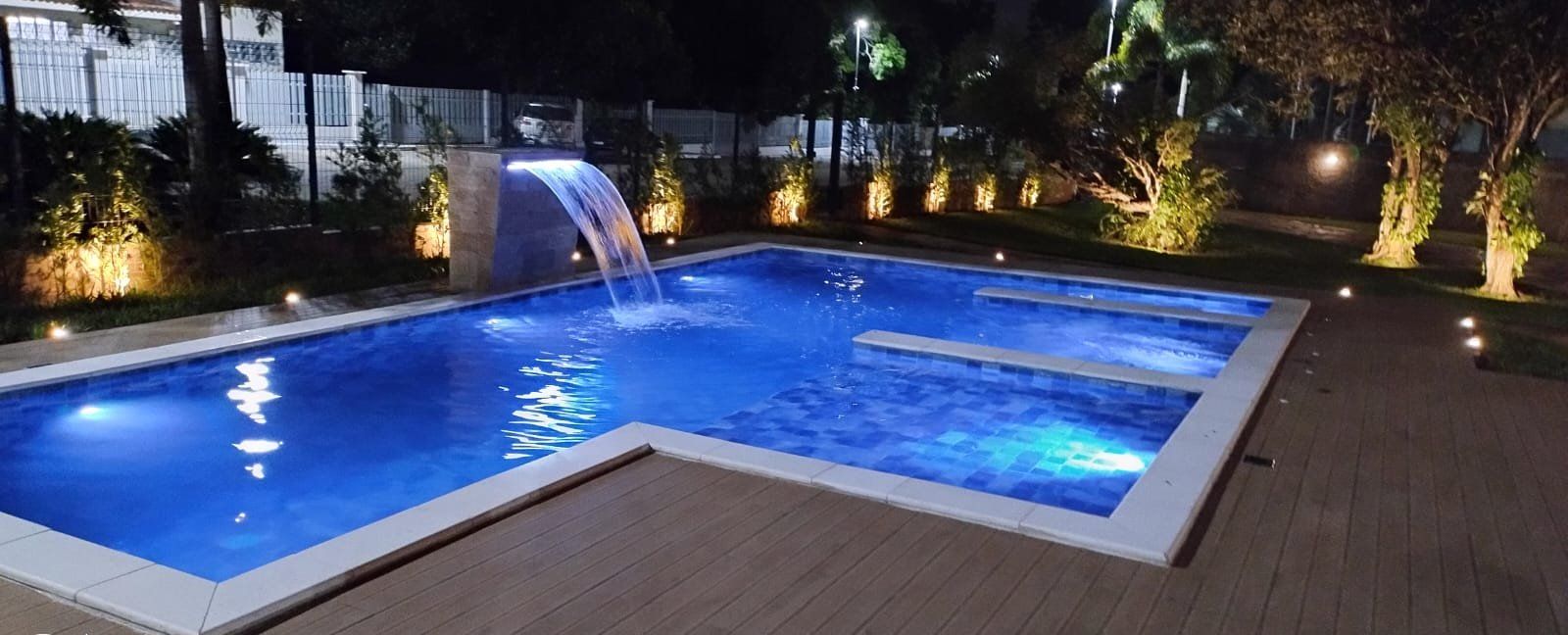Piscina com prainha, cascata e iluminação LED à noite em Brasília